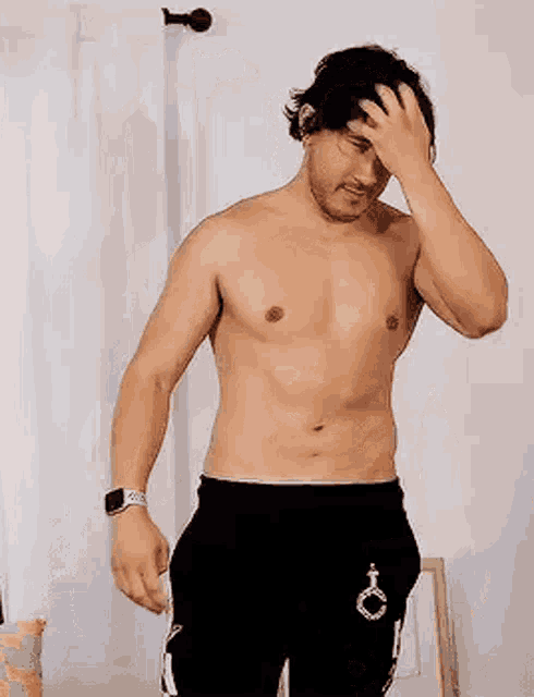a shirtless man is standing in front of a mirror in a room .