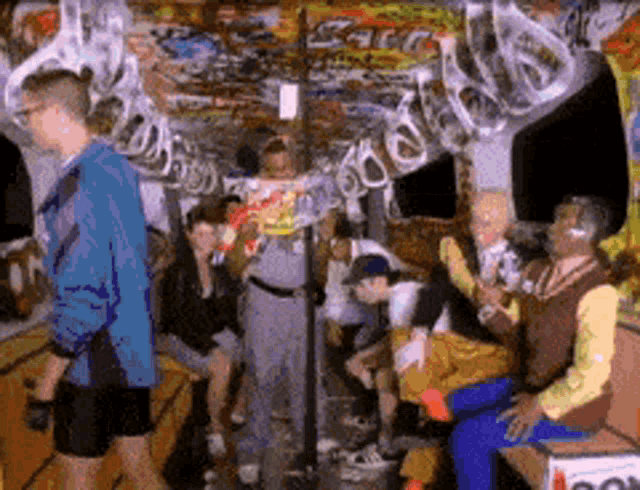 a group of people are gathered in a room with graffiti on the walls and a box that says ' coca cola '