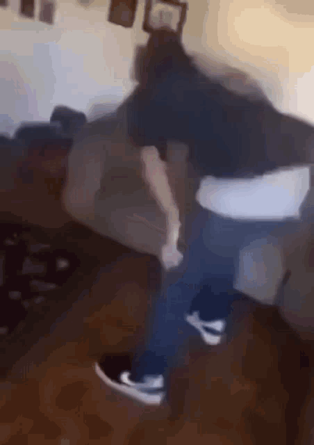 a man is dancing in a living room next to a couch .