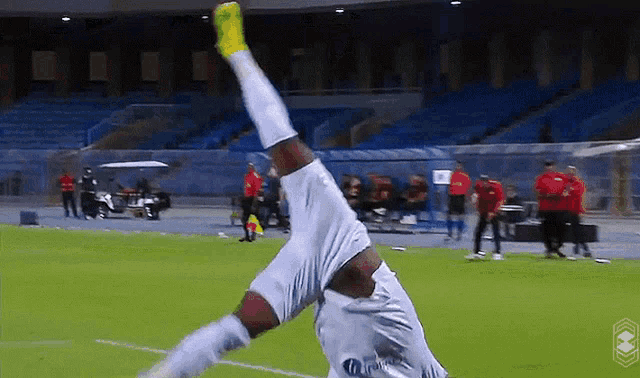 a soccer player is doing a handstand on the field while wearing a jersey that says ' gazprom ' on it