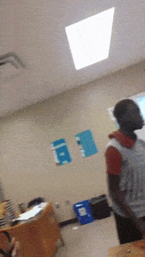 a person standing in a classroom with a sign on the wall that says a on it