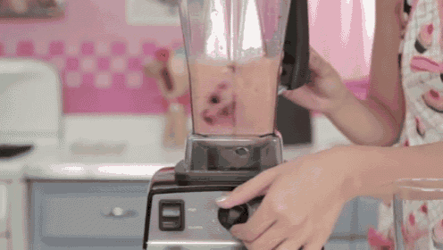 a woman is using a blender to make a smoothie in a kitchen