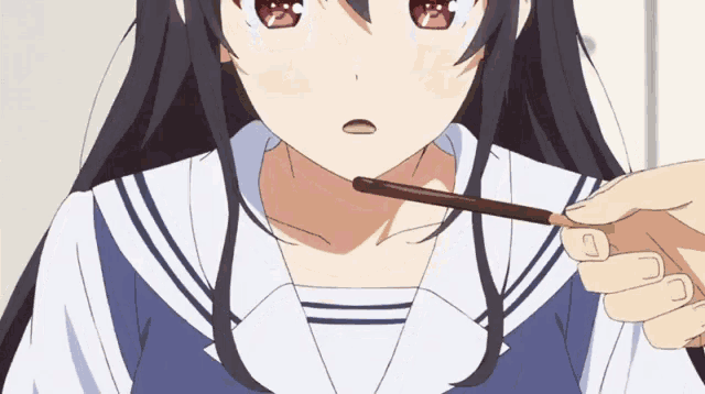 a girl in a sailor suit is eating a chocolate stick