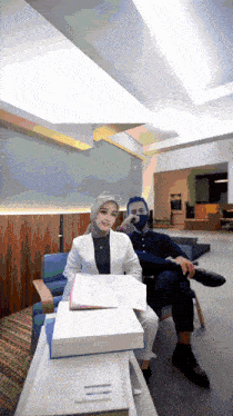 a woman in a hijab sits next to a man in a chair