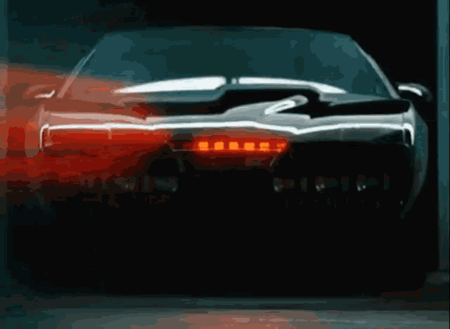 a black car with red lights on the back is parked in a dark garage .