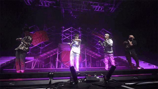 a group of people standing on a stage with purple lights behind them