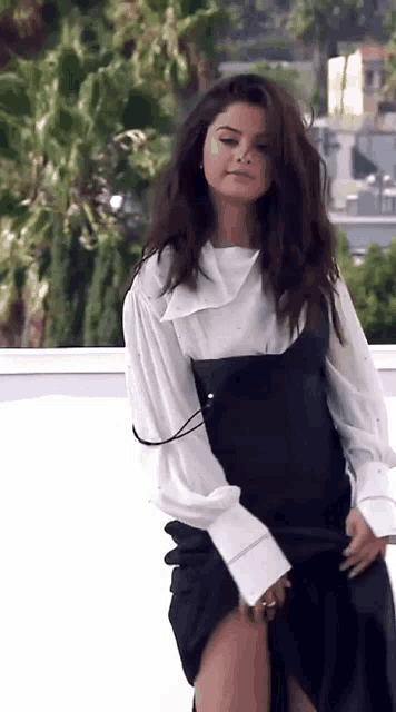 a woman is wearing a white shirt and a black skirt .