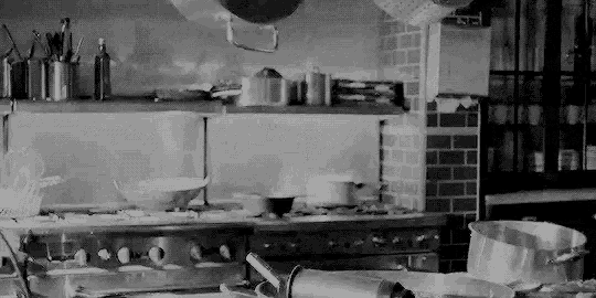 a black and white photo of a kitchen with pots and pans on a stove .