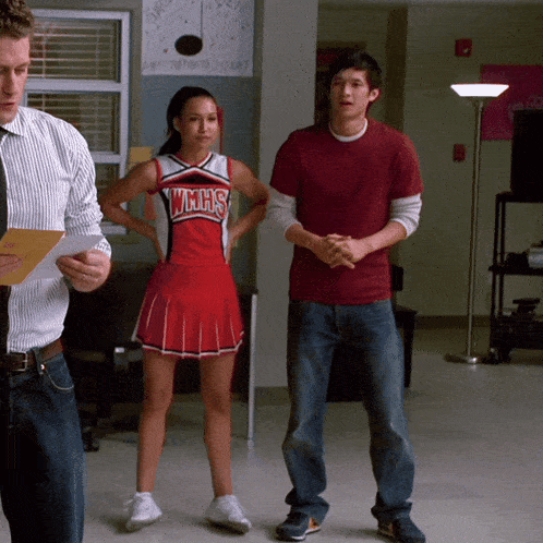 a cheerleader in a wmhs uniform stands next to a man in a red shirt
