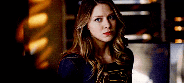 a woman in a superman costume is looking at the camera with a serious look on her face .