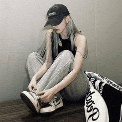 a woman wearing a black hat is sitting on the floor tying her shoes
