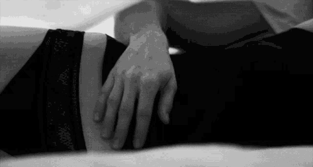 a man and a woman are laying on a bed holding hands .