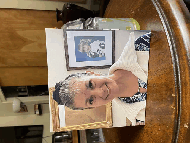 a picture of a woman sitting on a table next to a framed picture of a child with the letter b on his shirt