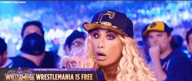 a woman in a baseball cap stands in front of a sign that says wrestlemania