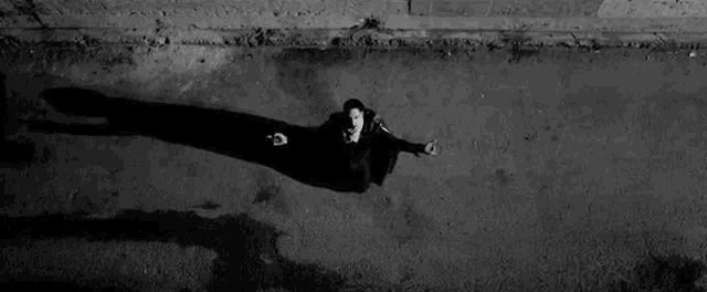 an aerial view of a man sitting on the ground with his shadow on the ground .