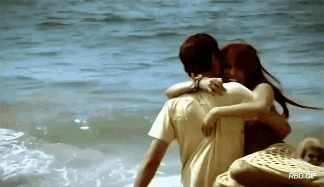 a gif of a man and woman hugging on the beach
