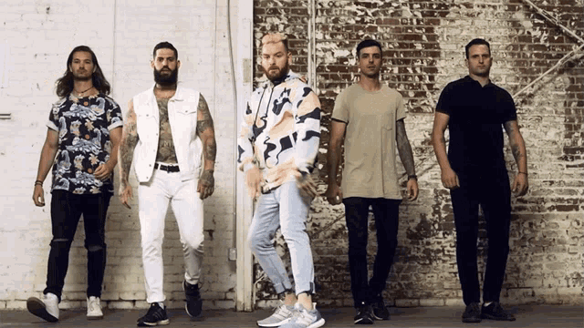 a group of men standing in front of a white brick wall