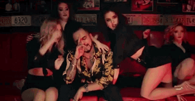 a group of women are sitting around a man on a couch in a club .