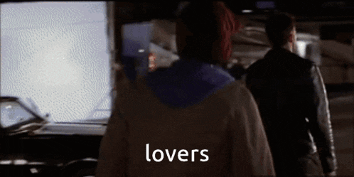 a man and a woman are standing in front of a car and the word lovers is on the screen