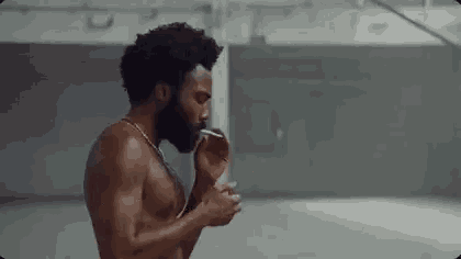 a shirtless man is smoking a cigarette in an empty room .
