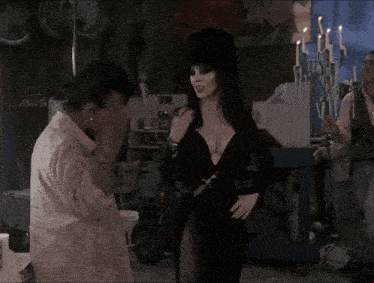 a woman in a black dress is standing next to a woman in a white coat
