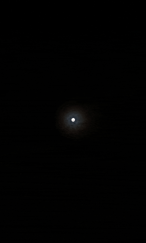 the moon is shining through the clouds in the dark night sky .