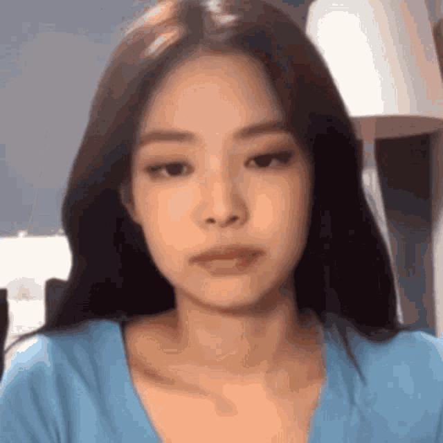 a close up of a woman 's face wearing a blue shirt and looking at the camera .