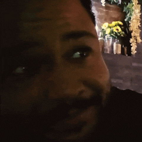 a close up of a man 's face with a blurred background of flowers