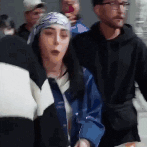 a woman wearing a bandana is standing in a crowd