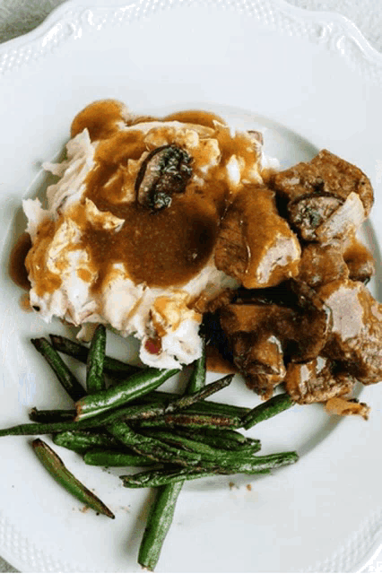 a white plate topped with green beans mashed potatoes and stew
