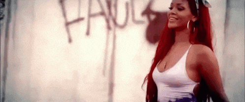 a woman with red hair is wearing a white tank top and earrings .