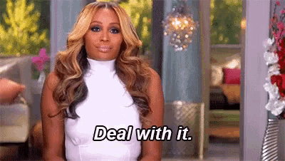 a woman in a white dress is sitting in front of a window and says `` deal with it '' .