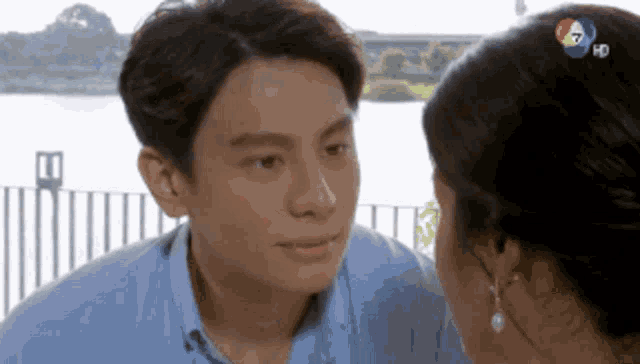 a man and a woman are looking at each other in front of a body of water