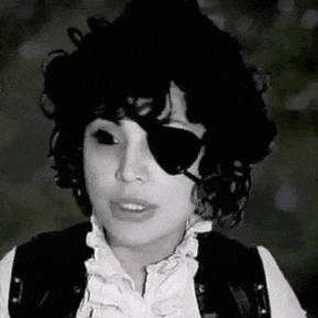 a black and white photo of a woman wearing a pirate costume and sunglasses .