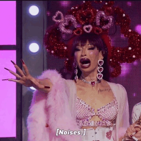 a drag queen is standing on a stage wearing a pink fur coat and a crown of hearts on her head .