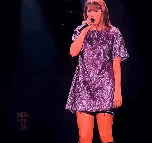 a woman in a purple sequined dress sings into a microphone