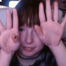 a woman is making a peace sign with her hands in front of her face