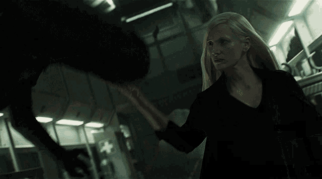 a woman in a black shirt is walking in a dark hallway