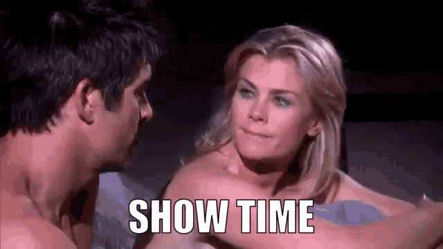 a man and a woman are laying on a bed and the woman is naked and the man is saying show time .