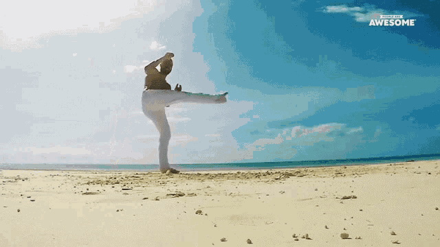 a man is kicking in the air on a beach with the word awesome behind him
