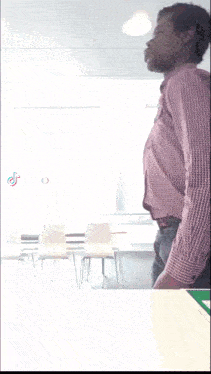 a man in a plaid shirt and black pants is standing in front of a white wall