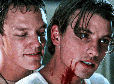 two men are standing next to each other and one has blood on his face