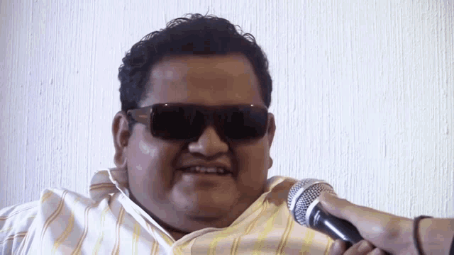 a man wearing sunglasses is being interviewed by a person holding a microphone