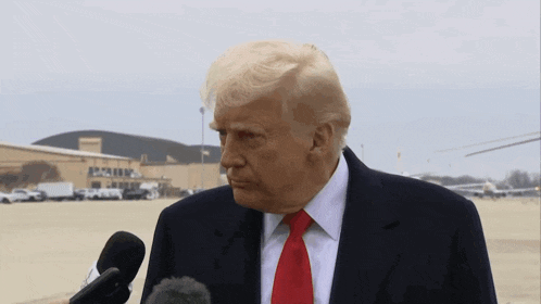 donald trump speaking into a microphone in front of a building that says ' apollo ' on it