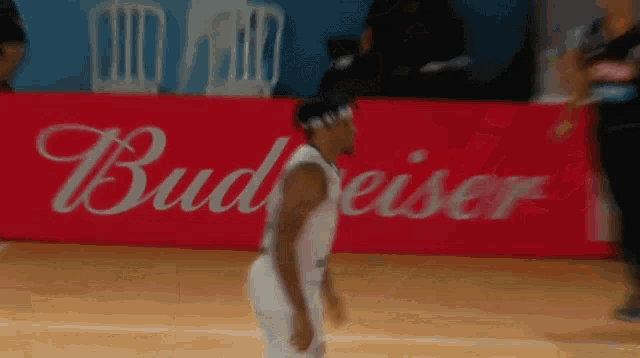a man playing basketball in front of a budweiser sign