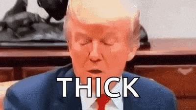 donald trump is sitting at a desk with his eyes closed and the word thick is written on his face .