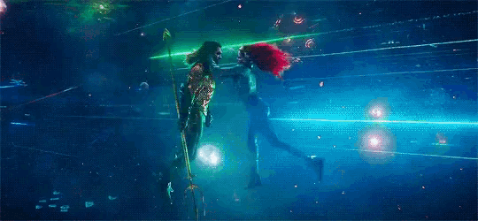 a man and a woman are kissing in the water while holding a spear