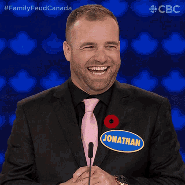 a man wearing a black suit and a pink tie has a name tag that says jonathan