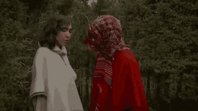 a man and a woman are standing next to each other in the woods .