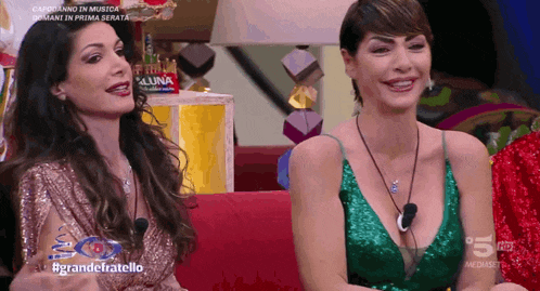 two women are sitting next to each other on a couch with the words #grandefratello on the screen